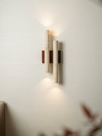 Soft light spills up and down from this Clérachic travertine wall light, with a blurred dark leaf in the corner.