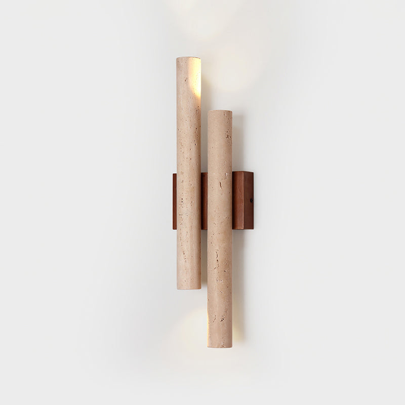 Close view of the lit Clérachic wall light, showing the pitted travertine tubes and the light from the open end of each.