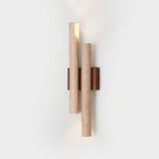 Close view of the lit Clérachic wall light, showing the pitted travertine tubes and the light from the open end of each.