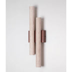 Unlit Clérachic wall light on a pale wall, its two long travertine tubes mounted on a dark walnut-wood plate.