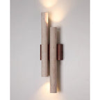 This Clérachic wall light is lit above and below, casting light along a pale grey wall from its two stone tubes.