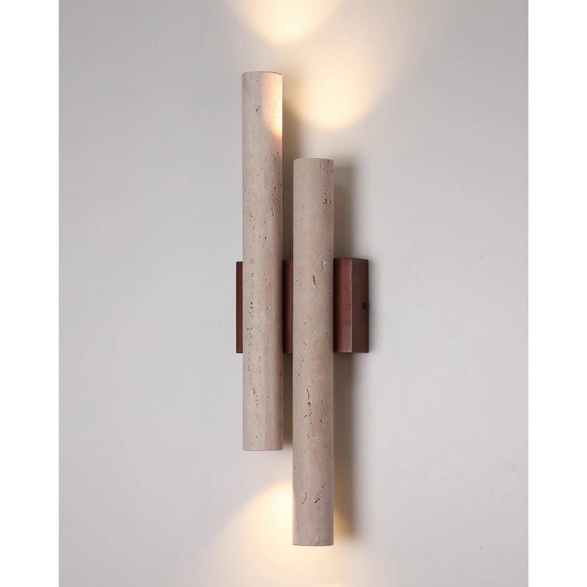 This Clérachic wall light is lit above and below, casting light along a pale grey wall from its two stone tubes.