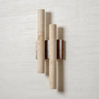 A Clérachic wall light on a white wall, its two travertine tubes showing natural pits and a walnut-wood backplate.
