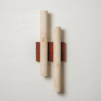 Straight-on view of this Clérachic wall light: two pale travertine tubes, one taller than the other, on a walnut plate.