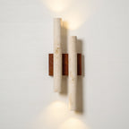 Lit Clérachic wall light on a white wall, with warm light thrown above the top tube and below the lower one.