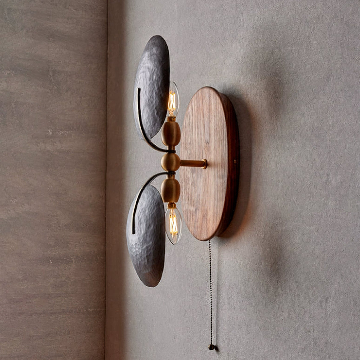 Side view of this Clérachic wall light, with two filament bulbs showing beside the dark shades and a brass-toned pull chain hanging below.