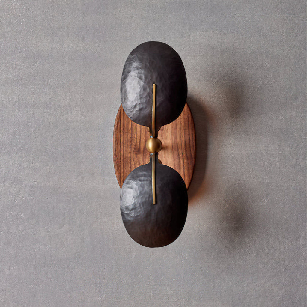 Front view of this Clérachic wall light, with a brass rod and ball joint between two dark shades on an oval walnut backplate.