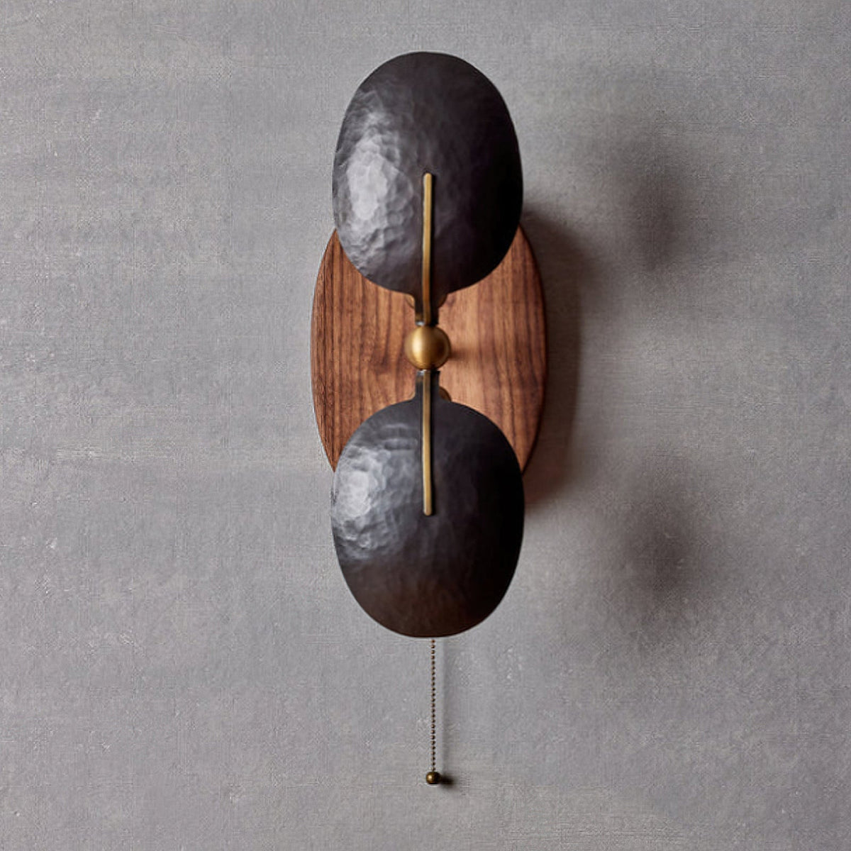 Unlit Clérachic wall light seen straight on, with two dark shades overlapping a walnut backplate and a beaded pull chain below.