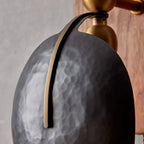 Close view of the hammered finish on one dark shade of this Clérachic wall light, with a slim brass strip down its face.
