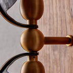 Close view of the brass ball joints and arm brackets that join the shades on this Clérachic wall light to its walnut backplate.
