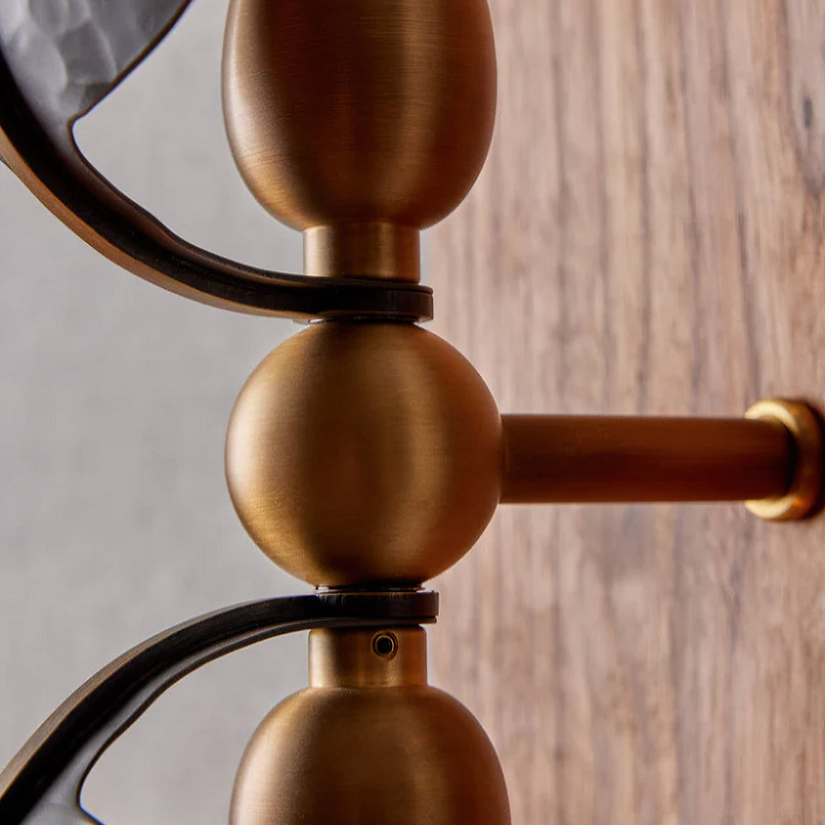 Close view of the brass ball joints and arm brackets that join the shades on this Clérachic wall light to its walnut backplate.