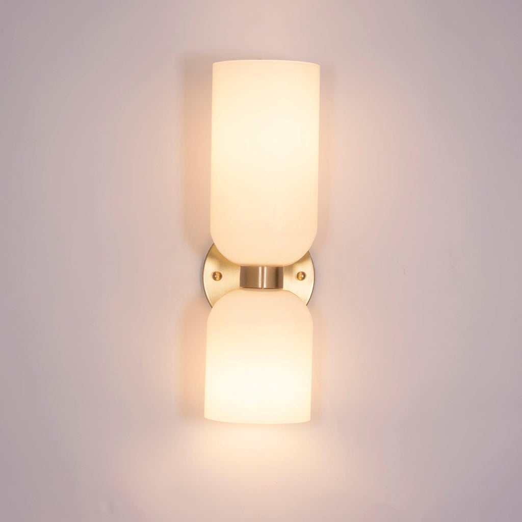 In a pale metal finish, this Clérachic sconce's opal shades glow against a soft pink wall.