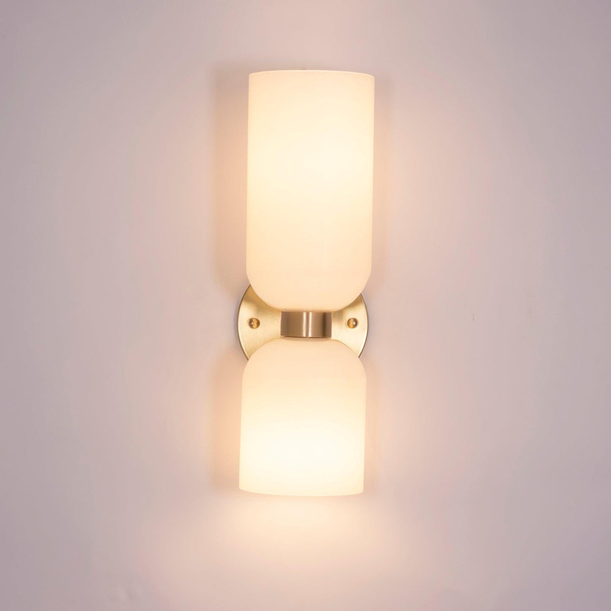 In a pale metal finish, this Clérachic sconce's opal shades glow against a soft pink wall.