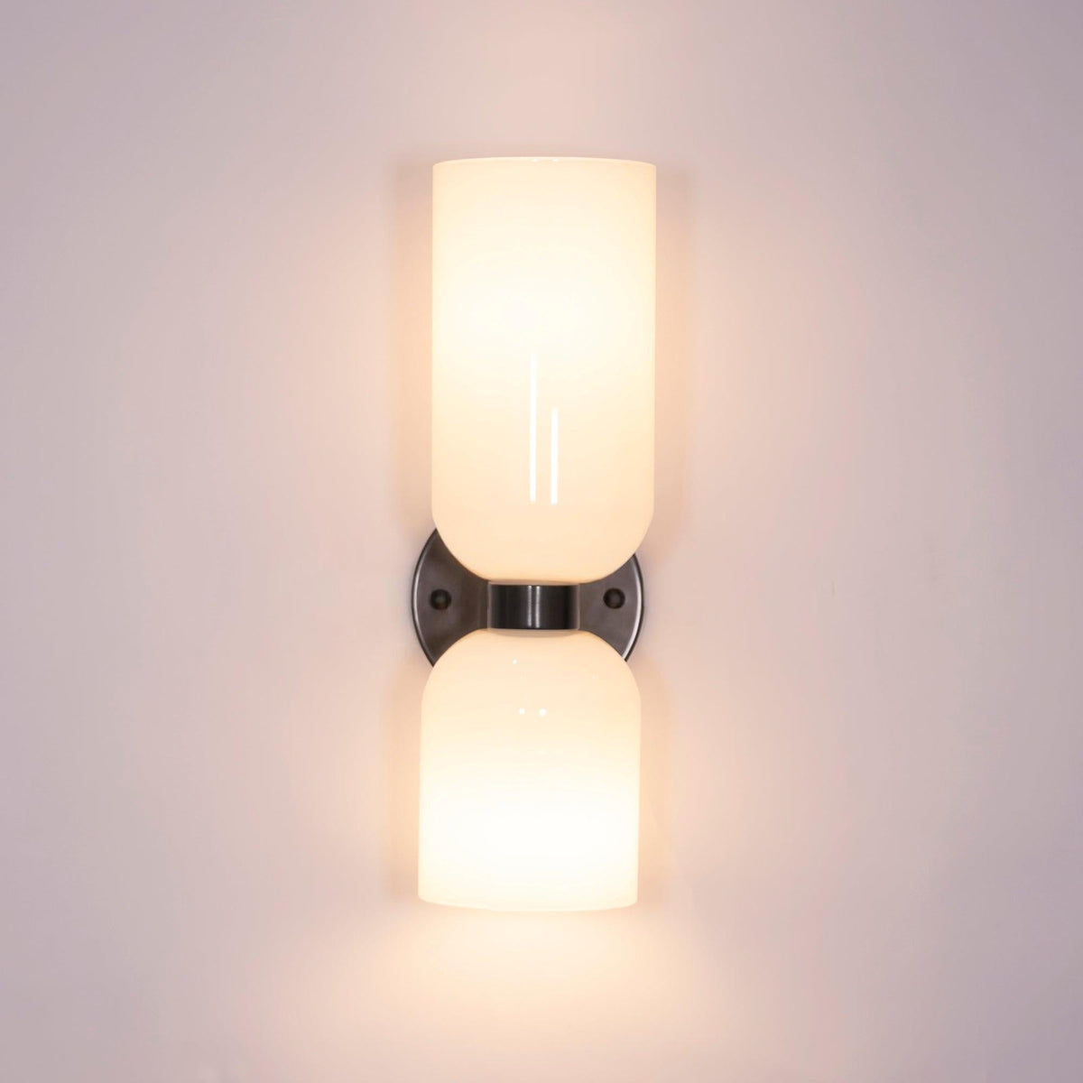 Lit against a lavender wall, the opal shades on this gunmetal Clérachic sconce cast a warm glow.