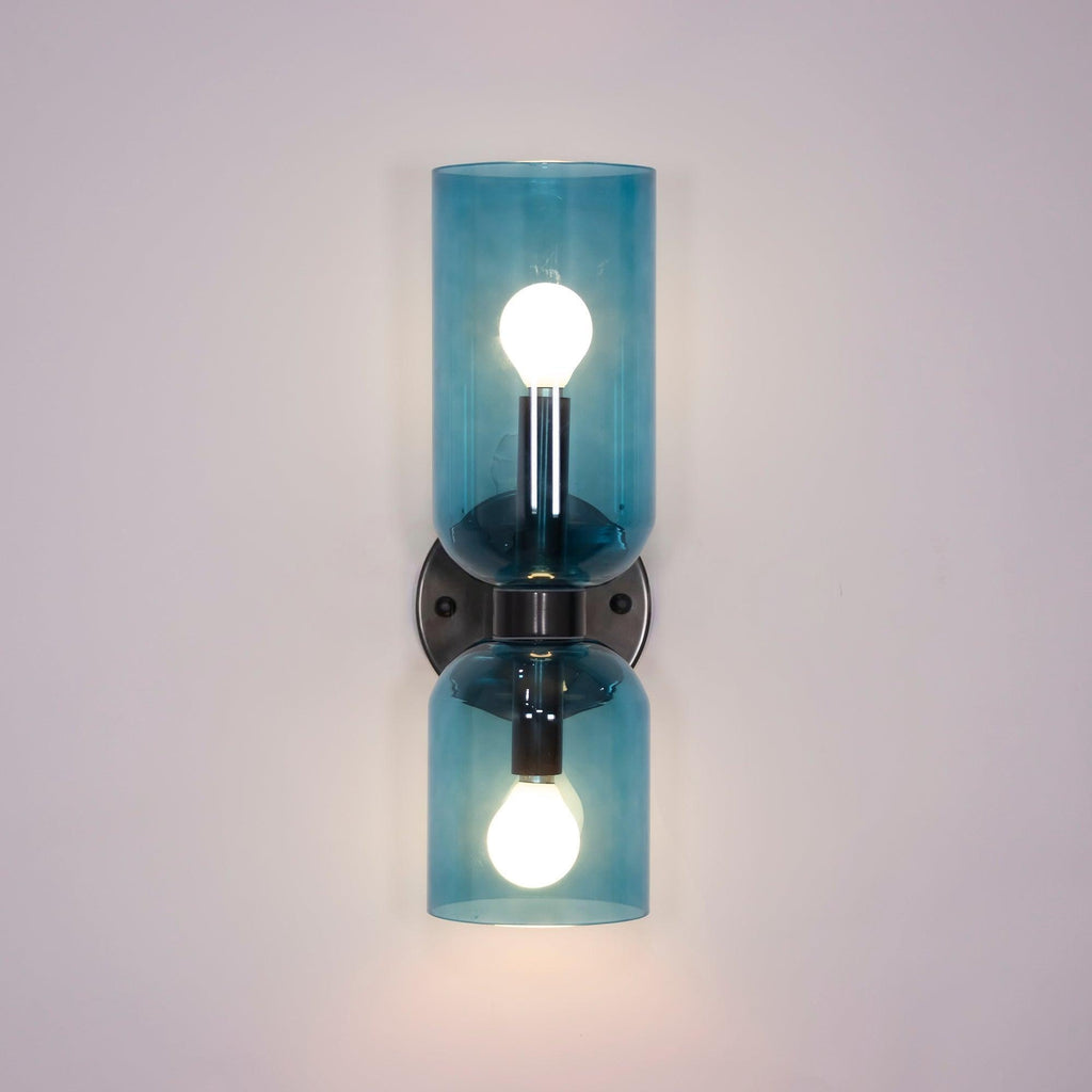 Exposed bulbs glow inside the blue glass cylinders of this matt black Clérachic wall light.