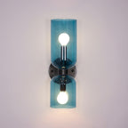 Exposed bulbs glow inside the blue glass cylinders of this matt black Clérachic wall light.