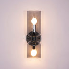 Smoke grey glass cylinders let the bulbs show through on this matt black Clérachic sconce.