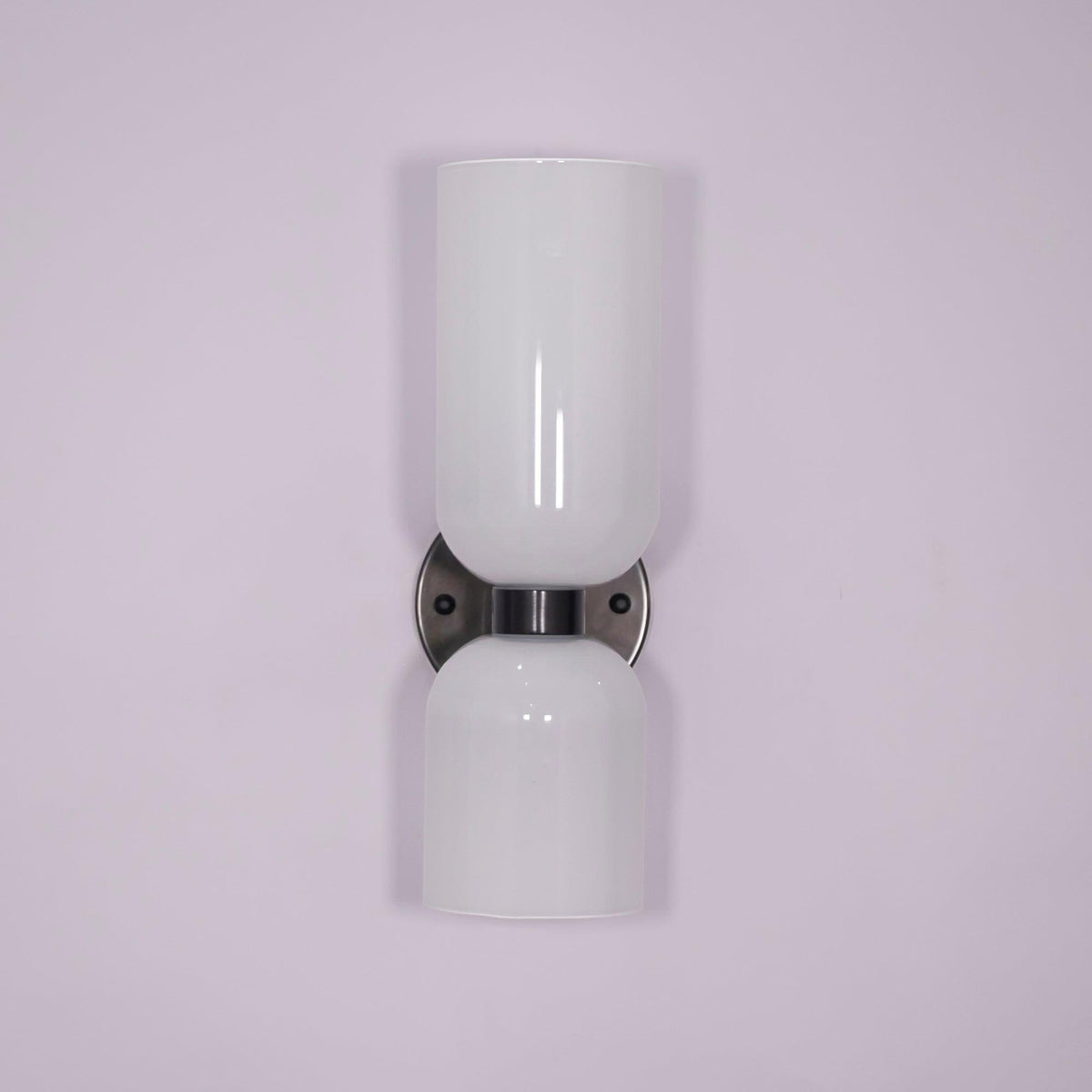 Unlit against a pale lilac backdrop, this gunmetal Clérachic wall light shows its opal glass shades.