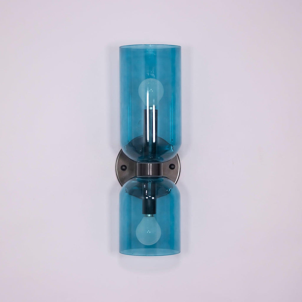 Blue glass cylinders trace this matt black Clérachic wall light against a soft lilac backdrop.