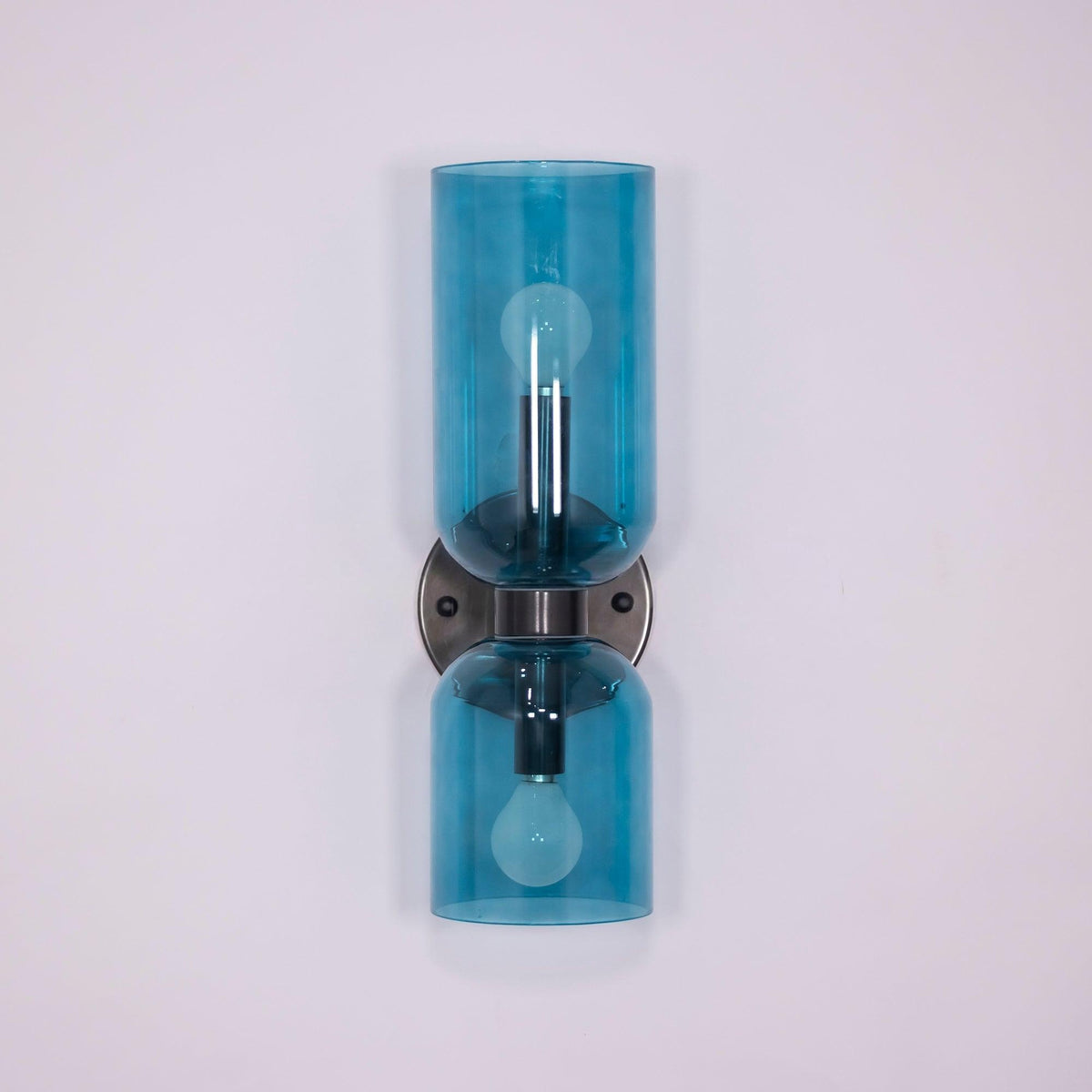 Blue glass cylinders trace this matt black Clérachic wall light against a soft lilac backdrop.