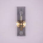 Smoke grey glass cylinders sit on this gold Clérachic wall light against a lilac backdrop.