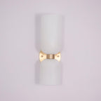 A tapered white glass shade tops this gold Clérachic sconce against a soft lilac backdrop.