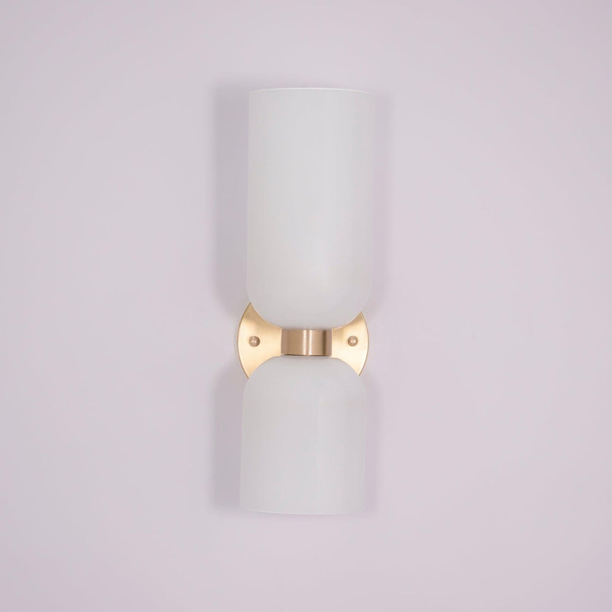 A tapered white glass shade tops this gold Clérachic sconce against a soft lilac backdrop.