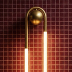Close view of the Clérachic wall light's brushed brass arch and round ball mount above two glowing frosted tubes on red tile.