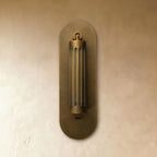 Clérachic fluted brass wall light seen straight on, the cylinder head hanging upright on its oval backplate