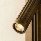 Close view of the Clérachic embedded wall light, a faceted LED lens in an aged brass fluted cylinder