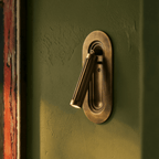 Clérachic embedded brass wall light on an olive green plaster wall, its fluted head angled down and lit