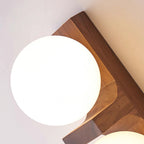 Close view of a frosted white glass globe on the walnut-coloured wood bracket of this Clérachic wall light, with the grain showing.