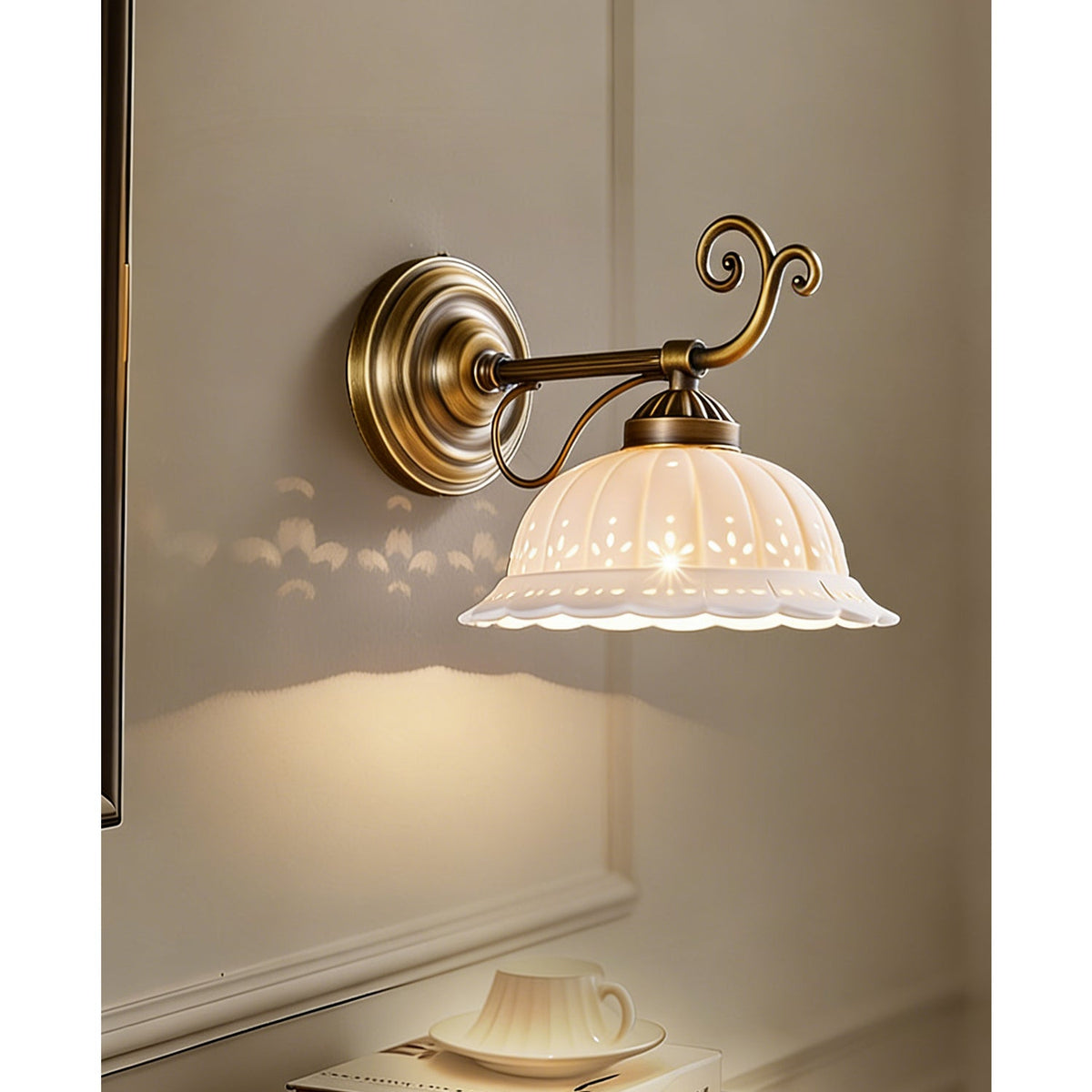 Above a teacup on a shelf, a Clérachic wall light lights its ribbed white ceramic shade from a brass arm that ends in a scroll.