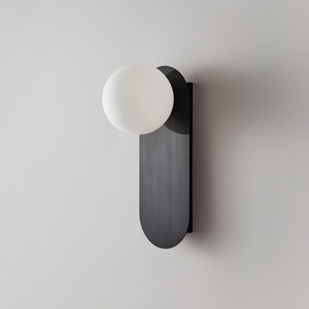 Unlit white frosted globe on a black brushed plate, this Clérachic wall light shown close on a light grey wall.