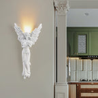 Standing-angel Clérachic wall light lit beside a fluted column, with a green kitchen visible through the open doorway.