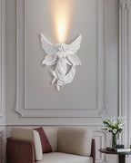 Lit fairy Clérachic wall light on a panelled wall above an armchair with a burgundy cushion and a vase of white flowers.