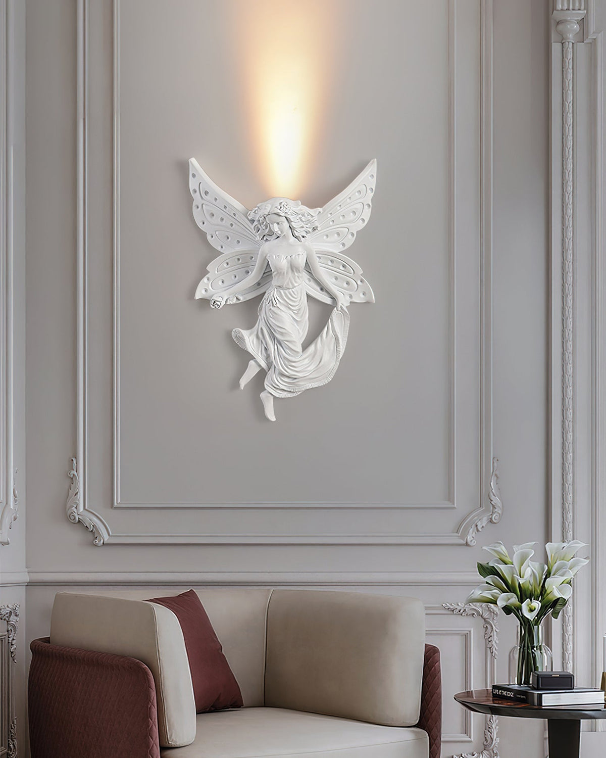 Lit fairy Clérachic wall light on a panelled wall above an armchair with a burgundy cushion and a vase of white flowers.