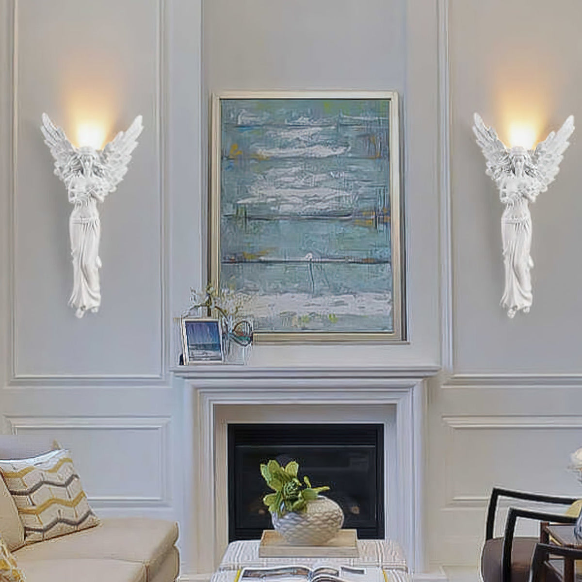 Two lit Clérachic angel wall lights flank a blue painting over a fireplace, in a room with a cream sofa and patterned cushions.