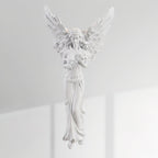 Unlit standing-angel Clérachic wall light on a sunlit white wall, its feathered wings and draped gown in white resin.