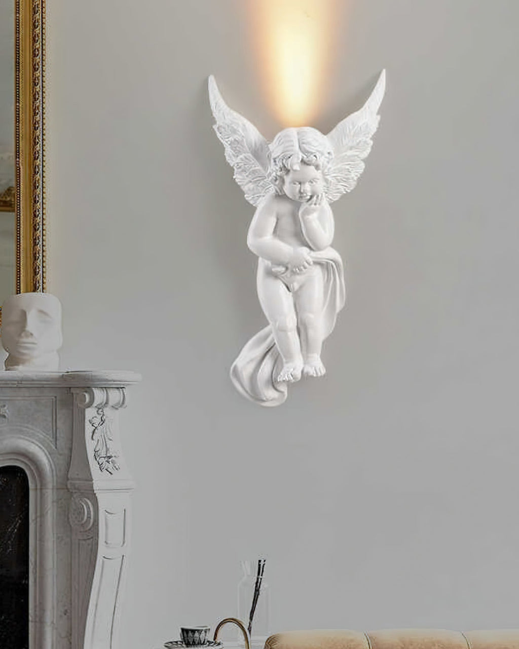 Cherub Clérachic wall light lit on a grey wall beside a marble fireplace, with a plaster bust on the mantel.