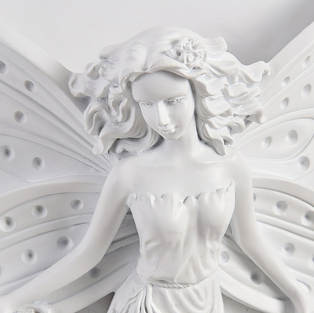 Close view of the fairy's face, flowered hair and perforated wings on this Clérachic white resin wall light.