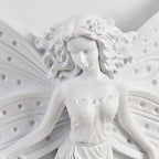 Close view of the fairy's face, flowered hair and perforated wings on this Clérachic white resin wall light.