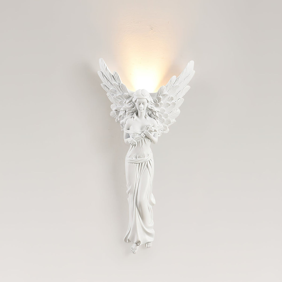 Standing-angel Clérachic wall light lit on a pale beige wall, a warm glow rising above its feathered wings.