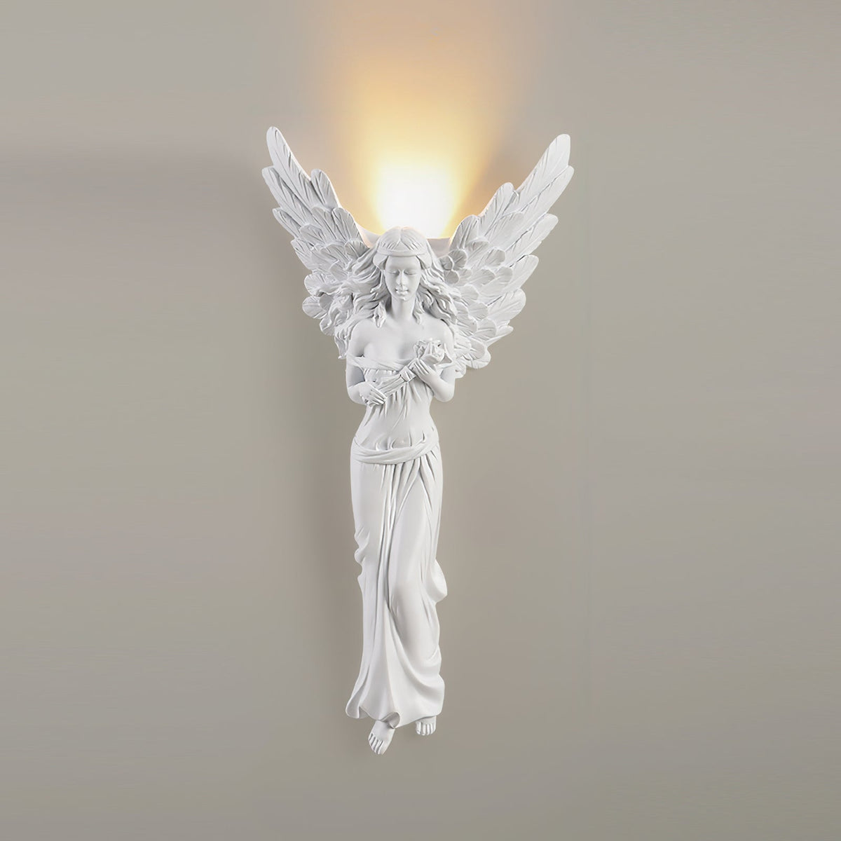 Lit standing-angel Clérachic wall light on a warm grey wall, the glow from above its wings softly lighting the wall.
