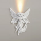 Fairy Clérachic wall light on a grey wall, lit, with a strong column of warm light rising above its butterfly wings.