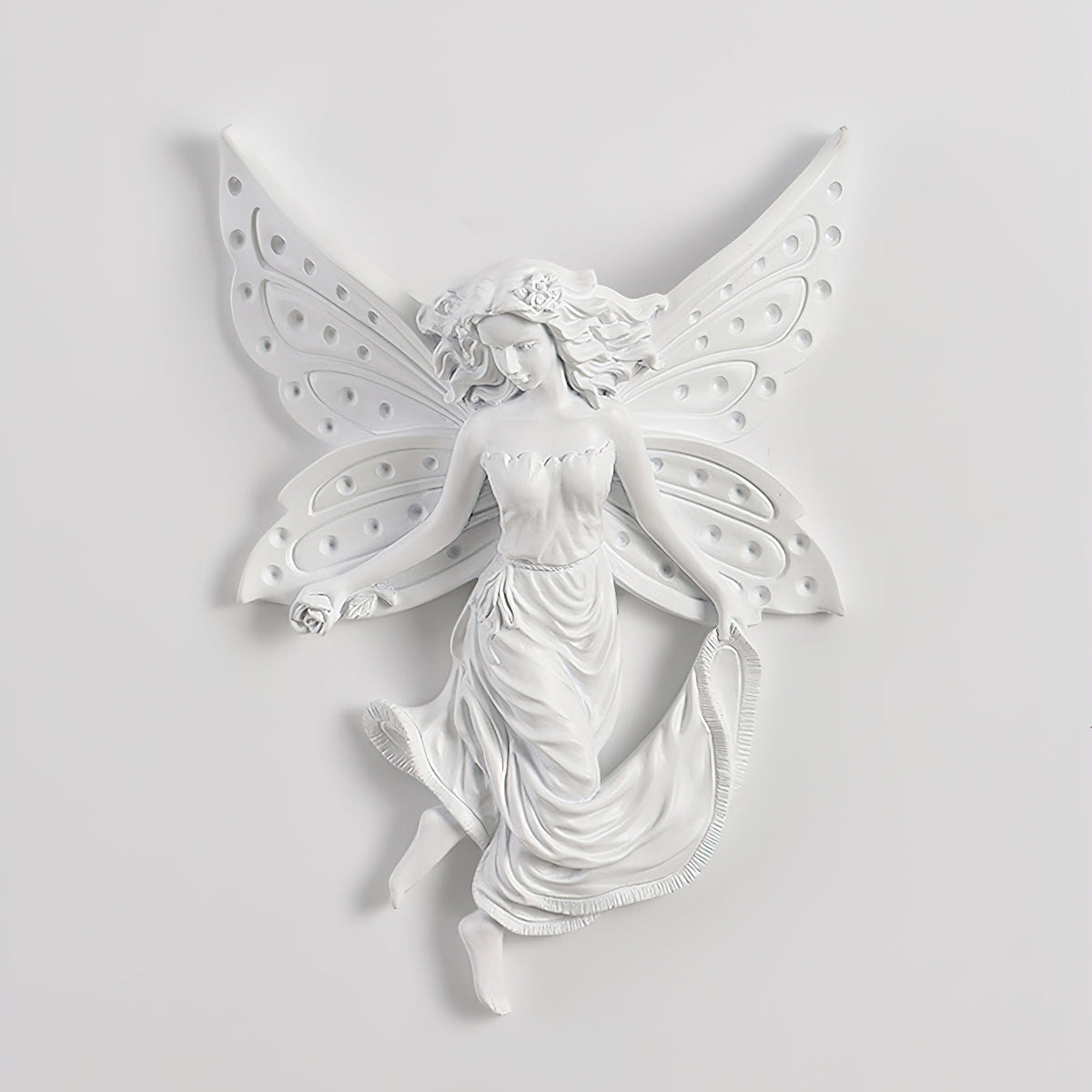 Unlit fairy-shaped Clérachic wall light on a pale wall, its perforated butterfly wings and flowing skirt in white resin.