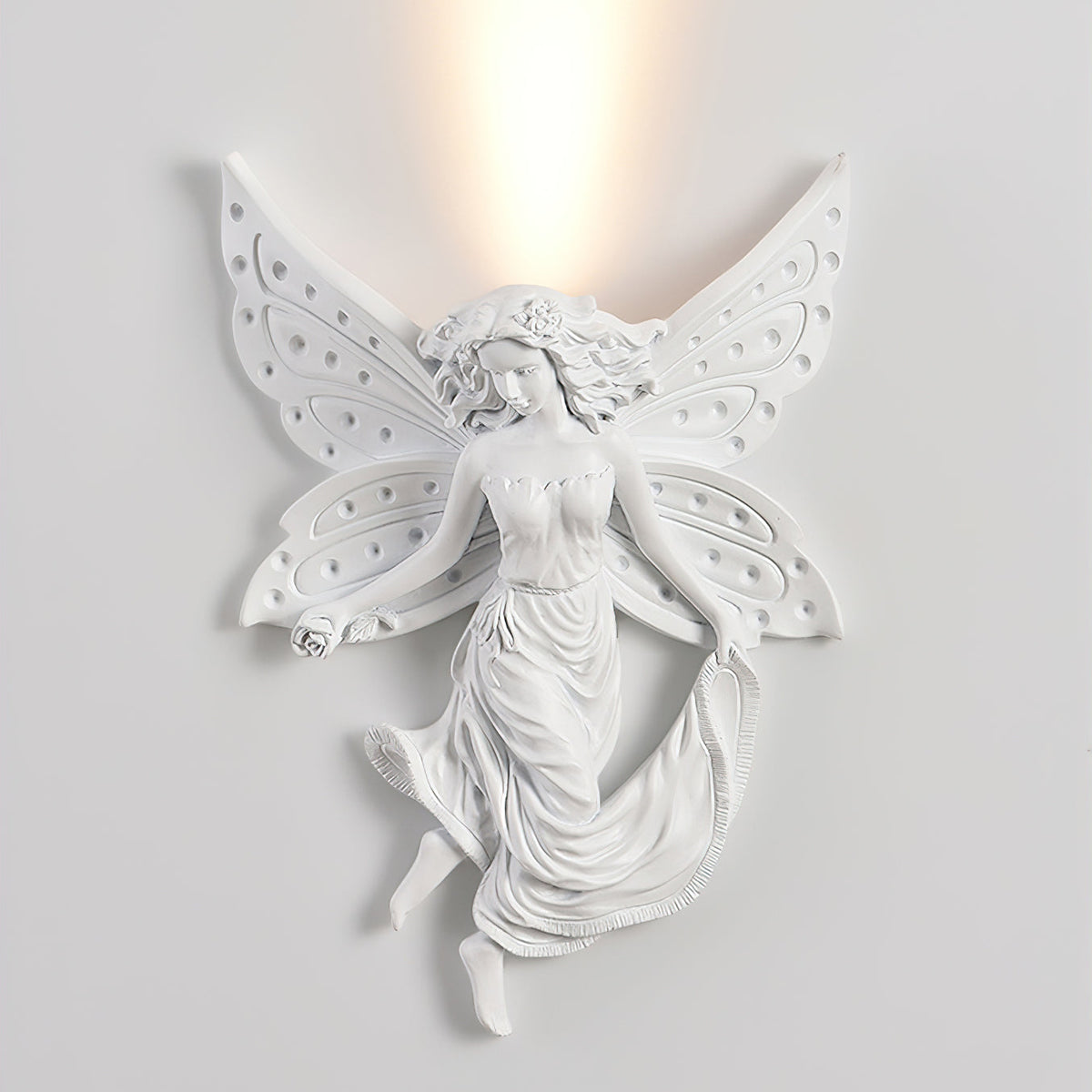 Lit fairy-shaped Clérachic wall light on a pale wall, the warm uplight spreading above its perforated wings.
