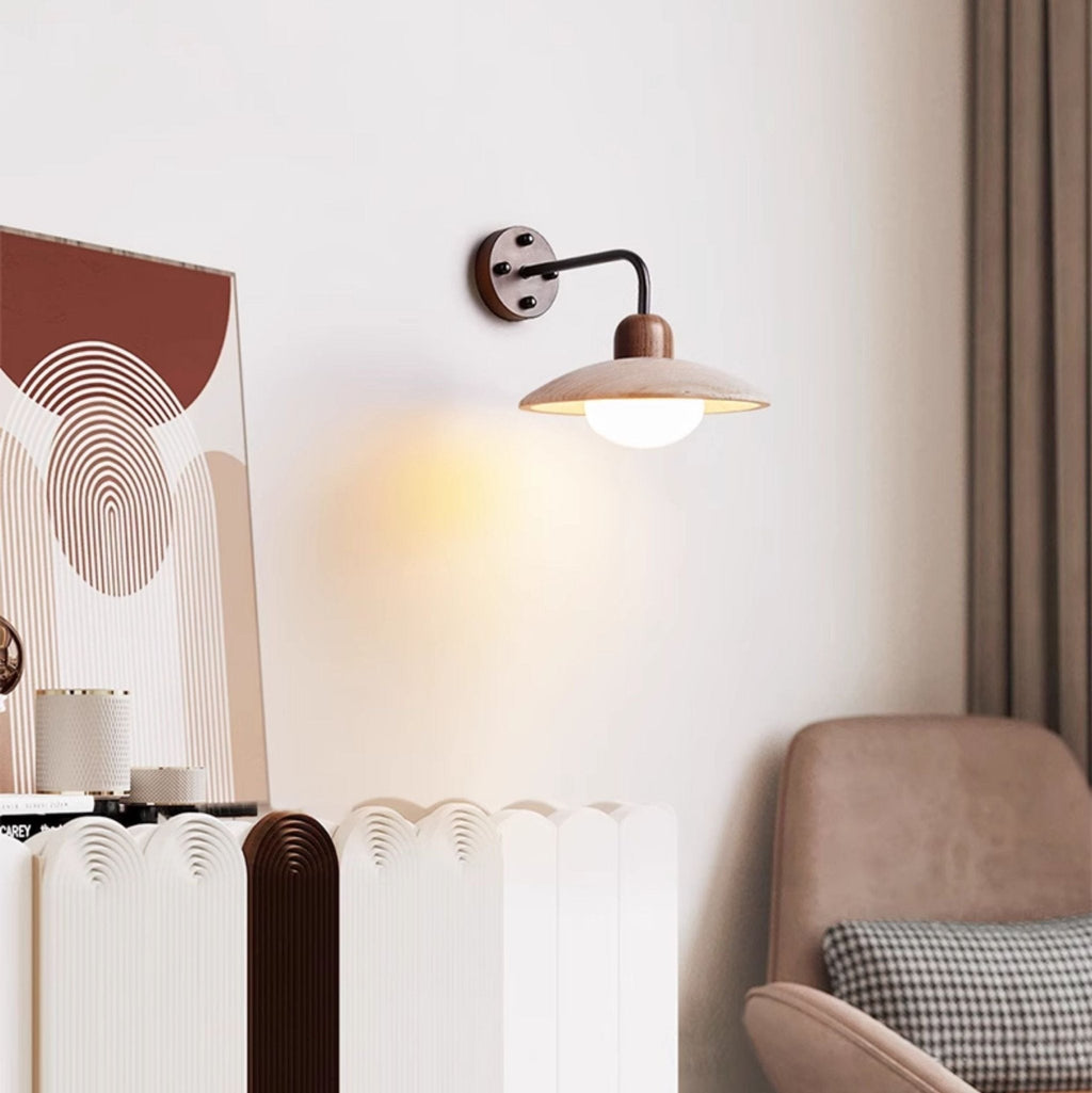 Clérachic wall light lit beside a framed arch-pattern print and a blush armchair with a houndstooth cushion.
