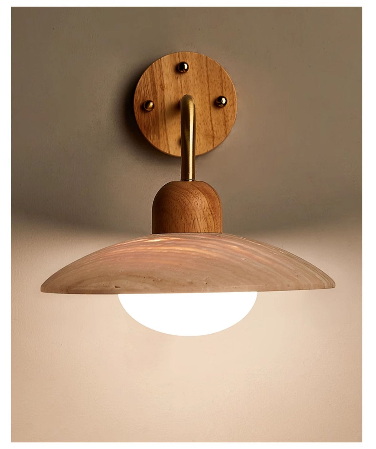 Clérachic wall light on a muted olive wall, its brass-toned arm dropping from a round wooden plate to a lit dome.