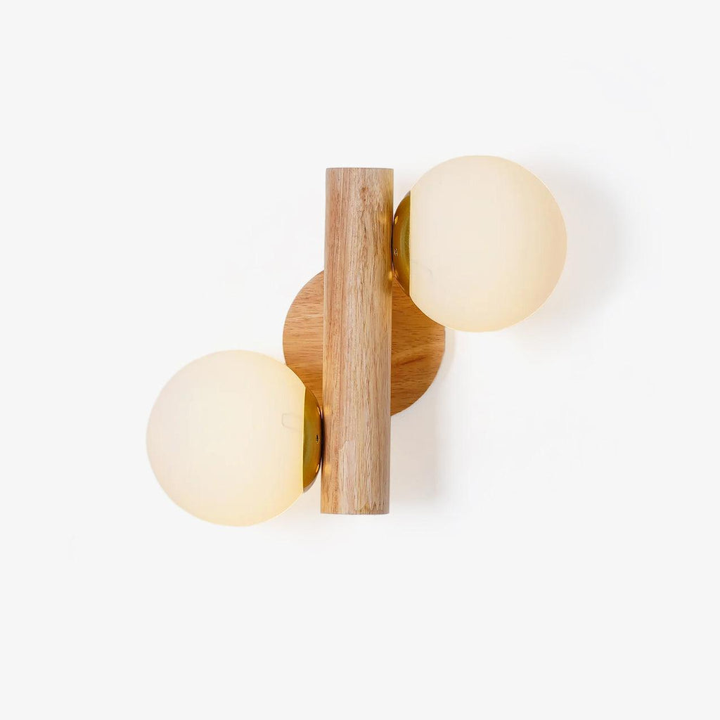 Wood wall sconce with two white glass globes on a vertical wooden rod, unlit, on a plain white backdrop, from Clérachic.